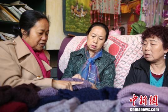 图为志愿者们讨论围脖的编织手法。　张海雯 摄