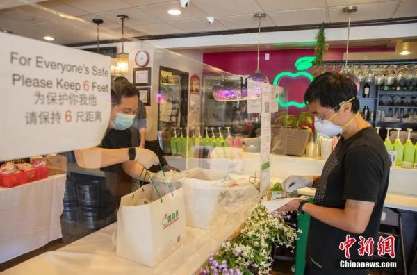 资料图：当地时间5月9日，美国硅谷腹地库比蒂诺商圈的“青苹果”餐厅在一条长桌上立起透明的挡板，店员与取餐者隔着挡板交流。中新社记者 刘关关 摄
